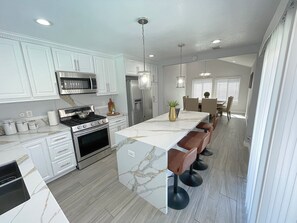 Modern marble rose quartz kitchen island with four barstools.