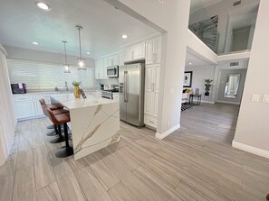 Modern marble rose quartz kitchen island with four barstools.