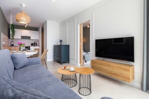 Another angle of the living room, showcasing the sofa, flat-screen TV, and a sleek wooden TV stand.
