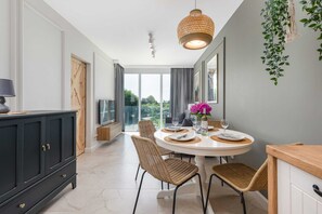 A dining area with a round wooden table, elegant chairs, and modern hanging lights, blending comfort and sophistication.
