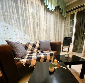 View of the living room with the sofa and coffee tables. Bright windows.