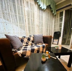 View of the living room with the sofa and coffee tables. Bright windows.