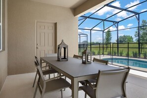 Relax and dine al fresco on this serene patio with pool views and lush greenery, perfect for unwinding under the open sky.