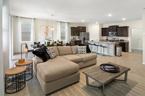Experience comfort and style in this open-plan living area with a cozy sectional, chic dining space, and modern kitchen—perfect for relaxing and entertaining.