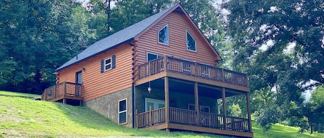 The cabin sits atop a hill in a wooded area