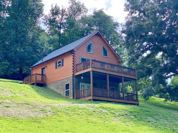 The cabin sits atop a hill in a wooded area