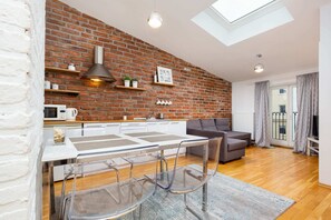 A dining and kitchen space with a table for four, surrounded by stylish exposed brick walls and natural light.
