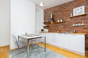 An open-plan kitchen with white cabinetry and shelves, blending functionality with industrial-style decor.
