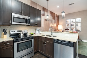 Fully furnished kitchen with all the necessities for basic cooking, including stainless steel appliances and a bar cart.
