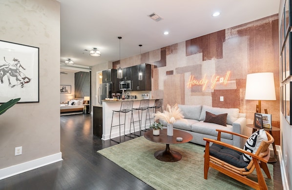 Bright and open-concept living area with designer furnishings, smart TV, and a sleeper sofa to accommodate additional guests.