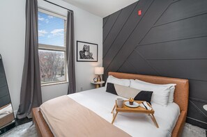 The primary bedroom features a King-sized bed, stylish furniture, and a smart TV.