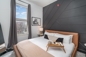 The primary bedroom features a King-sized bed, stylish furniture, and a smart TV.