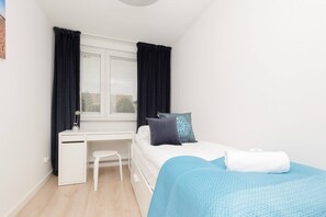 A bedroom with turquoise bedding and large windows, creating a serene and airy ambiance.
