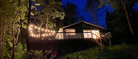 The cottage at night, from near the water.