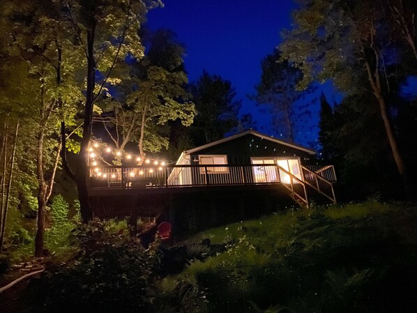 The cottage at night, from near the water.