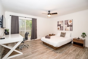 The primary bedroom has a full sized computer desk and chair. Mounted TV