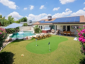 Backyard featuring pool, putting green, and outside dining area.