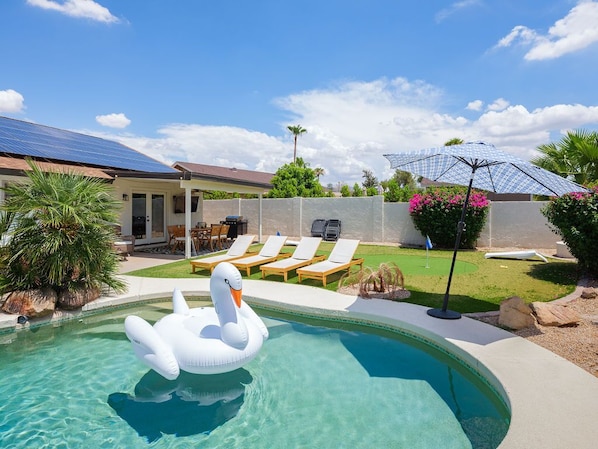 Backyard featuring pool, hot tub, putting green, and outside dining area.