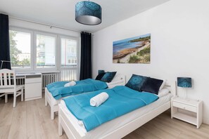 A bright bedroom featuring a double bed with turquoise bedding, bedside tables, and matching decor for a serene ambiance.
