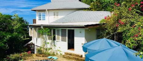 Side profile of house, surrounded by lush tropical plants.