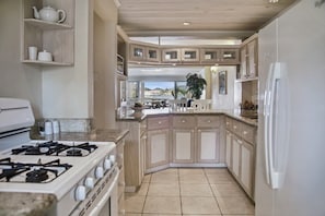 Fully equipped kitchen, looks out to over the living spaces and out to the water.