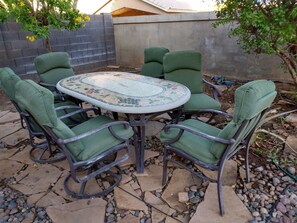 Outdoor furniture table with six chairs under the shade of lemon tree