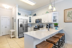 Spacious kitchen with modern appliances and barstool seating at the counter.