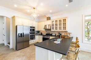 Spacious kitchen with a gas stove and barstool seating.