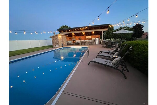 Large heated pool with outdoor lights and lounge chairs. 