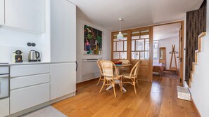 Modern white kitchen paired with a cozy wooden dining set, creating a welcoming space to enjoy meals. #ContemporaryCharm #CozyDining