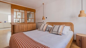 Stylishly furnished bedroom featuring a wooden bed frame, pendant lighting, and soft, earthy tones. #SereneEscape #ElegantDesign