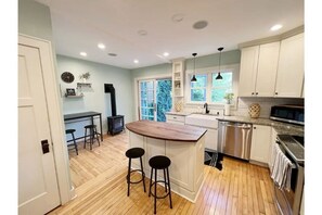 Spacious kitchen with breakfast bar, island and electric fireplace.