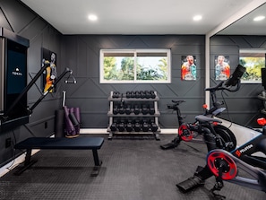Glass door Fitness room with two Pelotons, Tonal system, and free weights