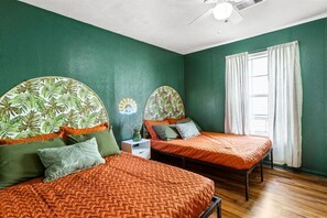 This bedroom has two comfortable double beds and a tropical vibe.