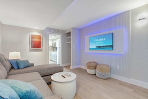 Relax in this cozy, living area featuring a plush sectional, accent lighting, and a Smart TV for entertainment. The soothing decor and comfortable seating make it an ideal spot to unwind after a day of exploring.