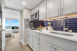 Modern kitchen with sleek cabinetry and a stylish blue-tile backsplash, fully equipped for your culinary needs. Just steps from the bedroom, this space offers convenience and functionality, allowing you to enjoy meals with a stunning ocean view.
