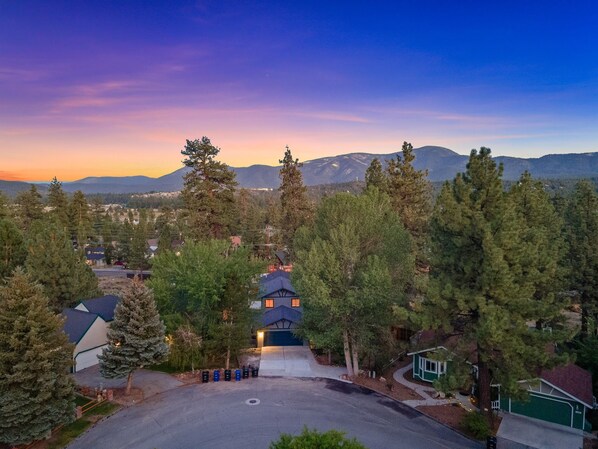 High-up view of the home from the street at sunset.