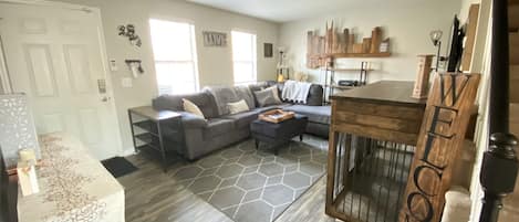 Large living room with dual dog kennel. Smart TV, sofa and chairs.