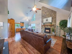 Cozy living space with mounted TV, fireplace, open concept kitchen space