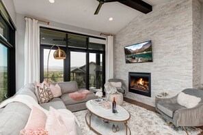 Living Room with plush sectional sofa, contemporary arm chairs, smart tv, gas fireplace, and private deck access