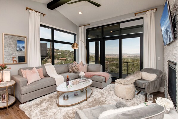 Living Room with plush sectional sofa, contemporary arm chairs, smart tv, gas fireplace, and private deck access