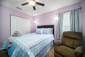 Unwind in this cozy lilac-hued haven with plush bedding and a recliner perfect for curling up with a good book or drifting into a peaceful nap~