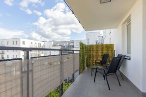 A spacious balcony with outdoor seating, offering views of the surrounding buildings.