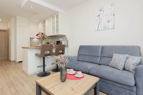 A cozy living room with a gray sofa, coffee table, and light wooden flooring, creating a warm and inviting atmosphere.