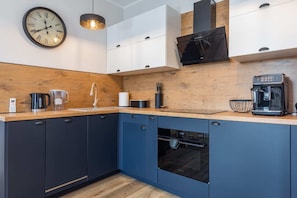 A sleek kitchen with dark blue cabinetry, wooden countertops, and modern appliances for a fully equipped experience.