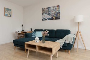 Another perspective of the living room, showcasing a teal sofa and wooden decor elements for a warm, inviting feel.
