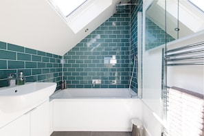 The en-suite bathroom is decorated with marine green tiles and modern fixtures.