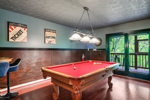 [Game Room / Lower level] Rack up some fun in our game room outfitted with a classic pool table and arcade machines—your playful hideout surrounded by nature's beauty.