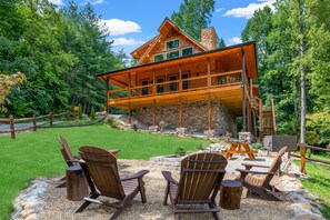 Sideview of cabin and flag stone picnic area, firepit & grill. Infront of pond.