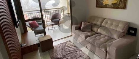 Sala de estar com smart TV, sofá retrátil e poltrona